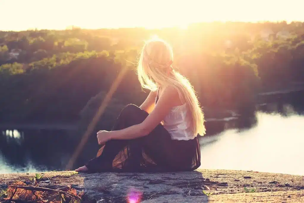 woman staring out over lake into sunset