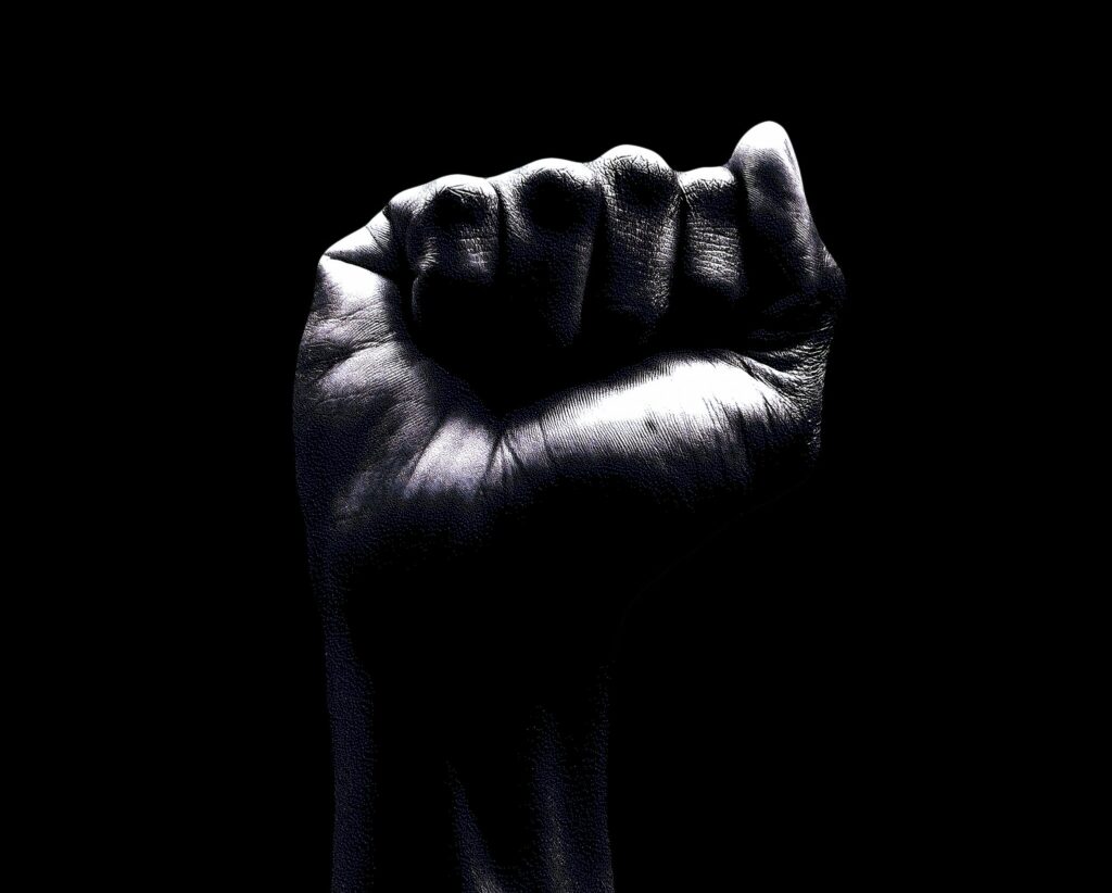 A raised clenched fist emerging from darkness, symbolizing anger, strength, and emotional power being brought into awareness.