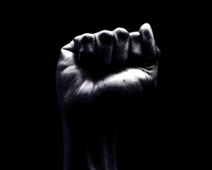 A raised clenched fist emerging from darkness, symbolizing anger, strength, and emotional power being brought into awareness.